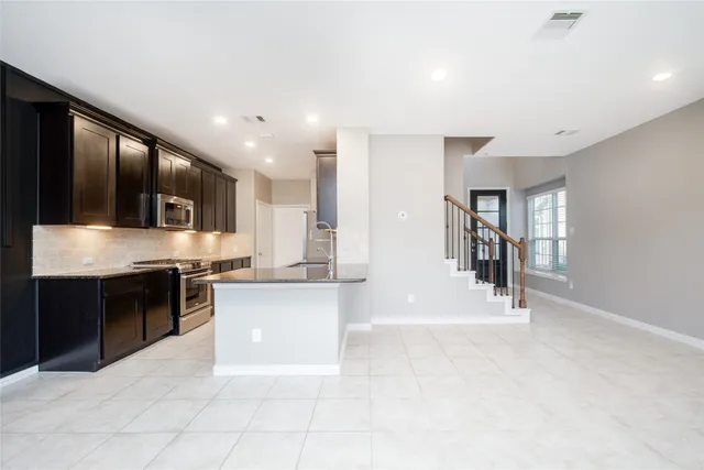 a large white kitchen with stainless steel appliances granite countertop a stove and a sink