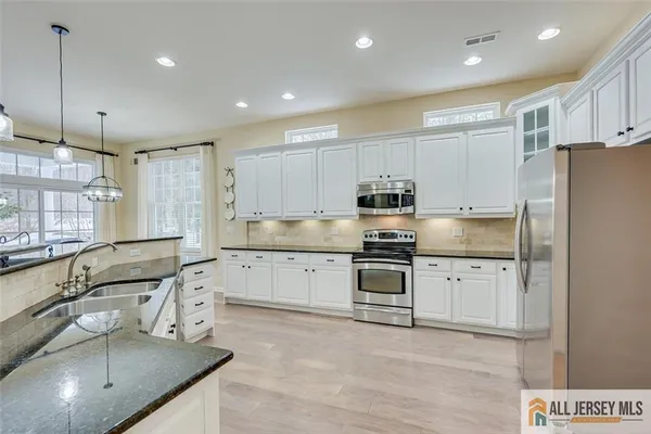 a kitchen with granite countertop a sink stainless steel appliances and cabinets