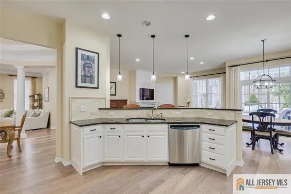 a kitchen with granite countertop a stove a sink a dining table and chairs with wooden floor