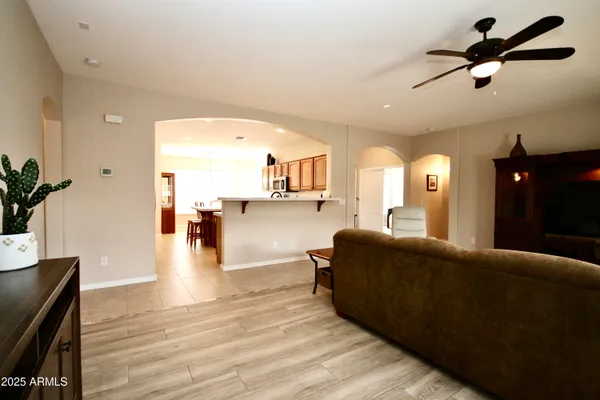 a living room with couches and kitchen view with wooden floor