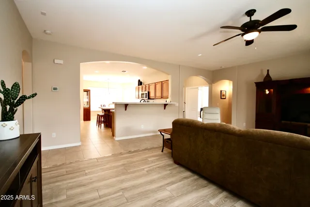 a living room with couches and kitchen view with wooden floor