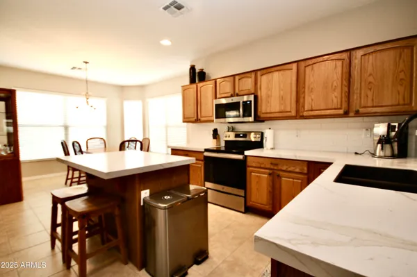a kitchen with stainless steel appliances kitchen island a table chairs in it and a sink