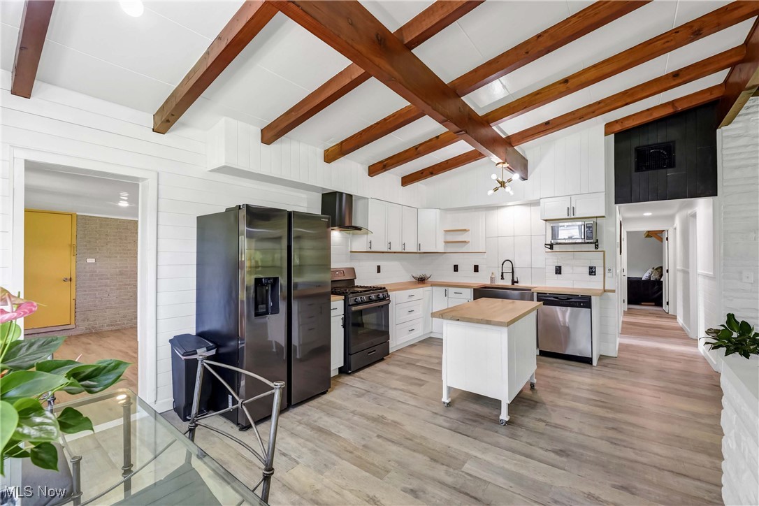 View of kitchen, center island and slate fridge / range / range hood, stainless dishwasher.