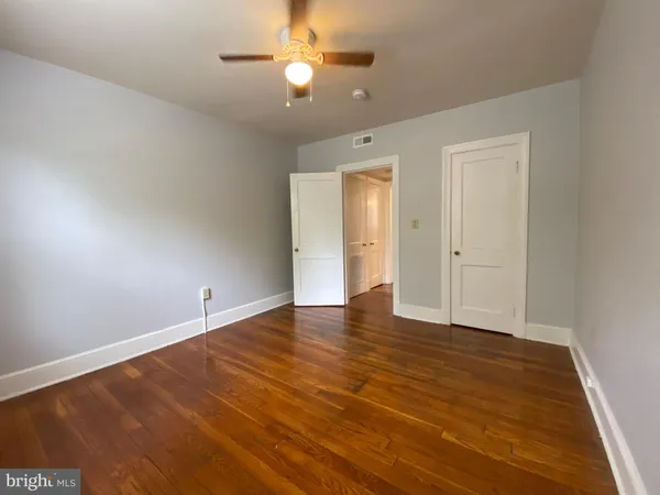 an empty room with wooden floor and fan
