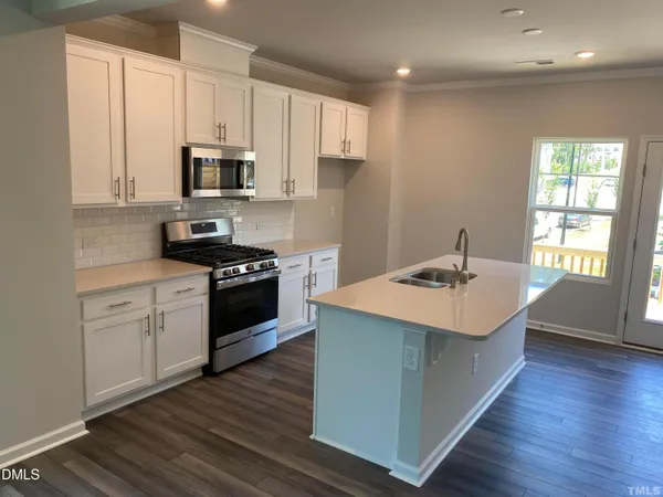 a kitchen with stainless steel appliances white cabinets a sink dishwasher and a stove with wooden floor