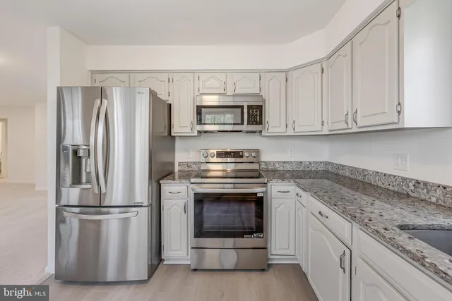 a kitchen with granite countertop a refrigerator stove and microwave