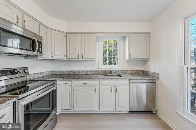 a kitchen with stainless steel appliances granite countertop white cabinets and a stove top oven