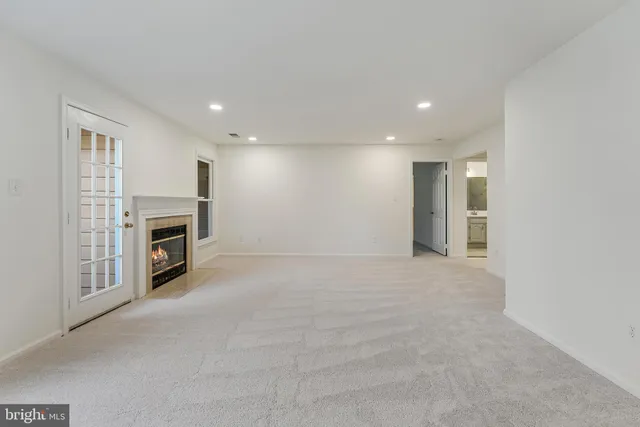 a view of a livingroom with a fireplace a ceiling fan and windows
