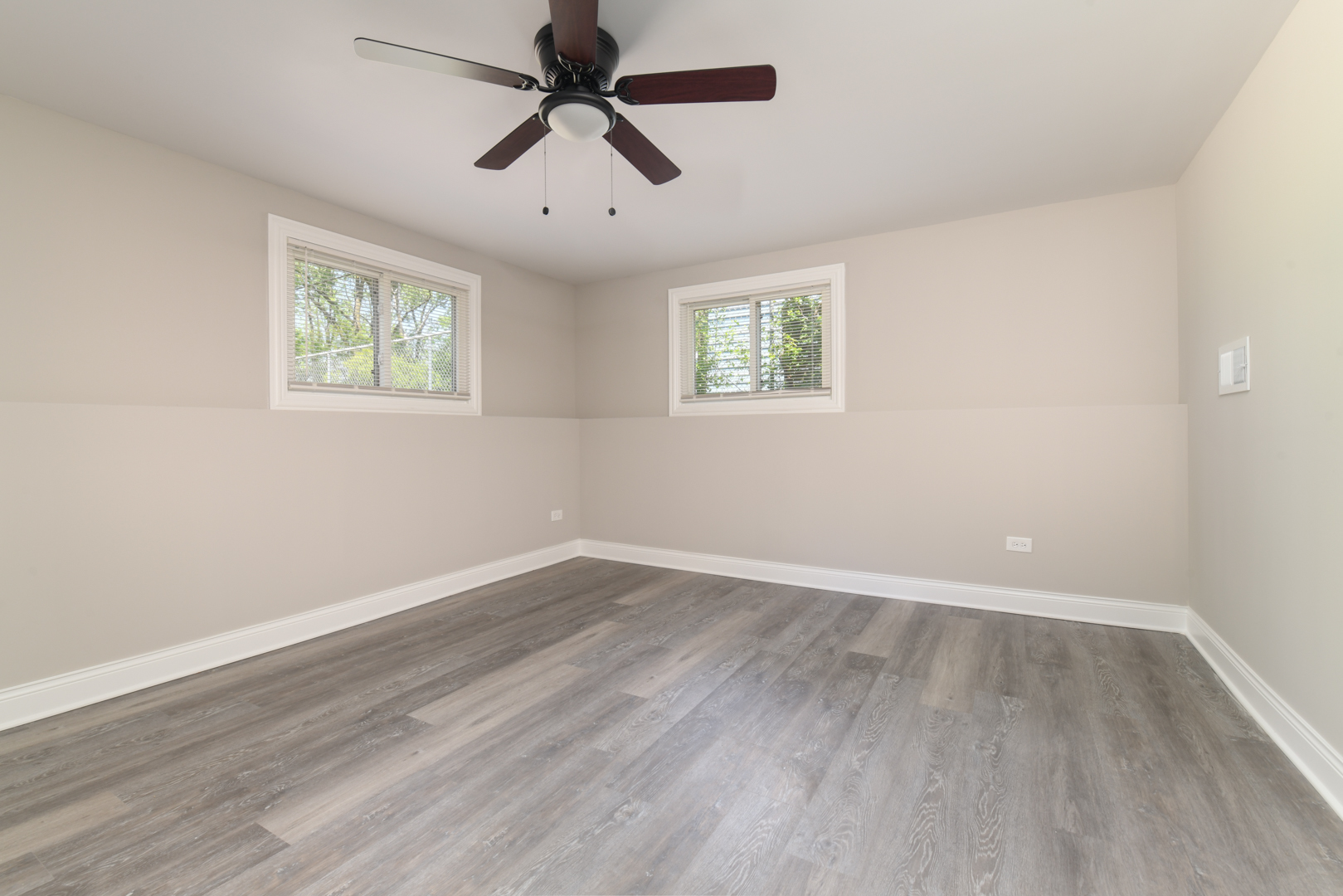 3402 Roesner Drive Markham, IL 60428 - Photo 16 of 23 an empty room with wooden floor ceiling fan and windows