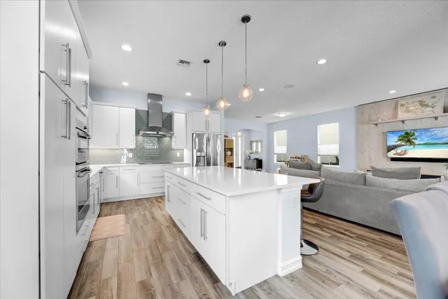 a large kitchen with stainless steel appliances kitchen island a large counter top and a view of living room