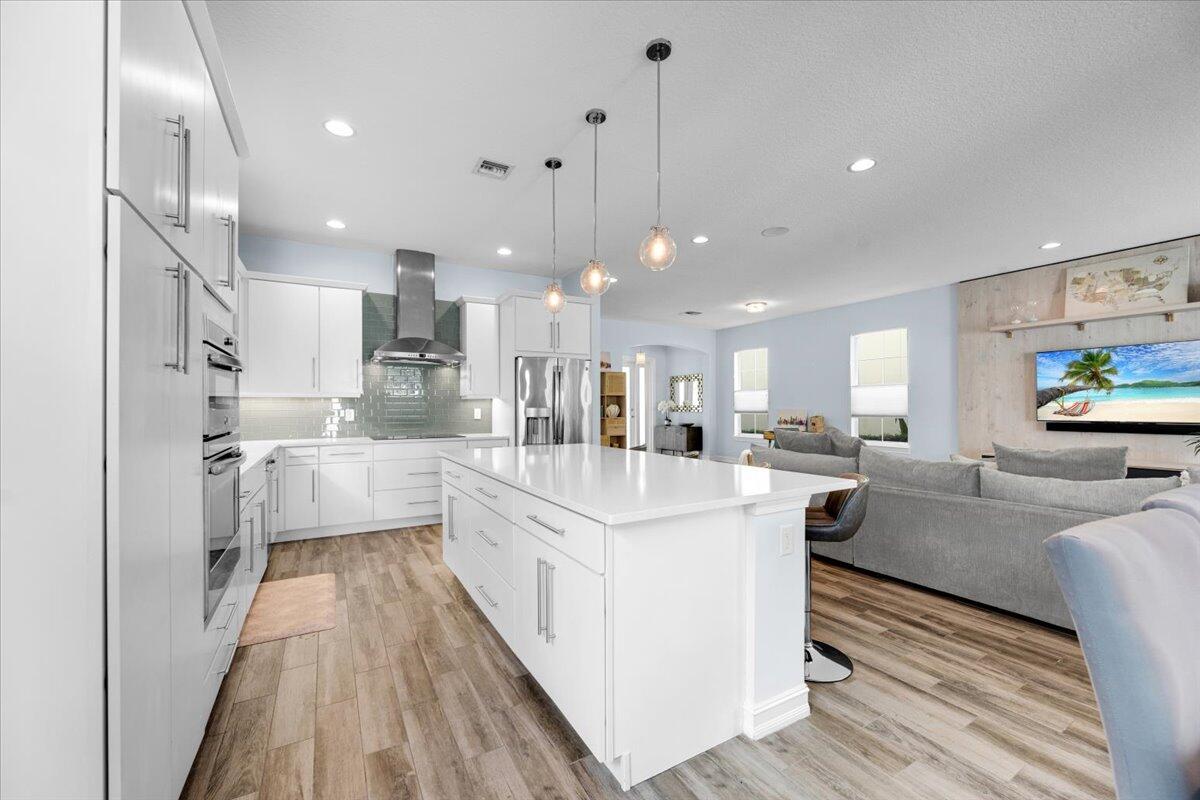 120 West Bay Cedar Circle Jupiter, FL 33458 - Photo 7 of 33 a large kitchen with stainless steel appliances kitchen island a large counter top and a view of living room