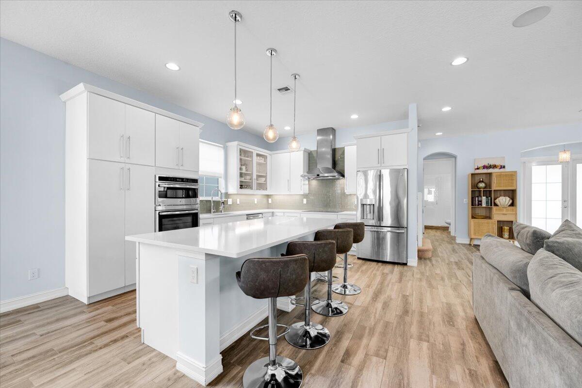 120 West Bay Cedar Circle Jupiter, FL 33458 - Photo 8 of 33 a kitchen with stainless steel appliances kitchen island granite countertop a refrigerator a stove a sink a dining table and chairs with wooden floor