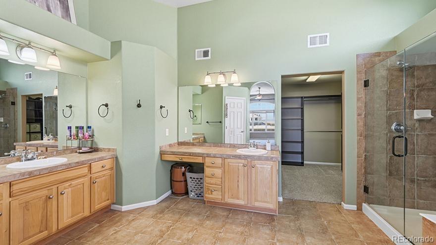 7869 Solstice Way Castle Rock, CO 80108 - Photo 21 of 41 a spacious bathroom with a granite countertop sink a mirror and a shower