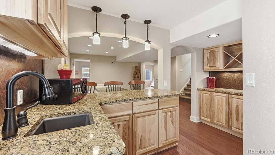 7869 Solstice Way Castle Rock, CO 80108 - Photo 33 of 41 a kitchen with stainless steel appliances granite countertop a sink a stove and a wooden floors