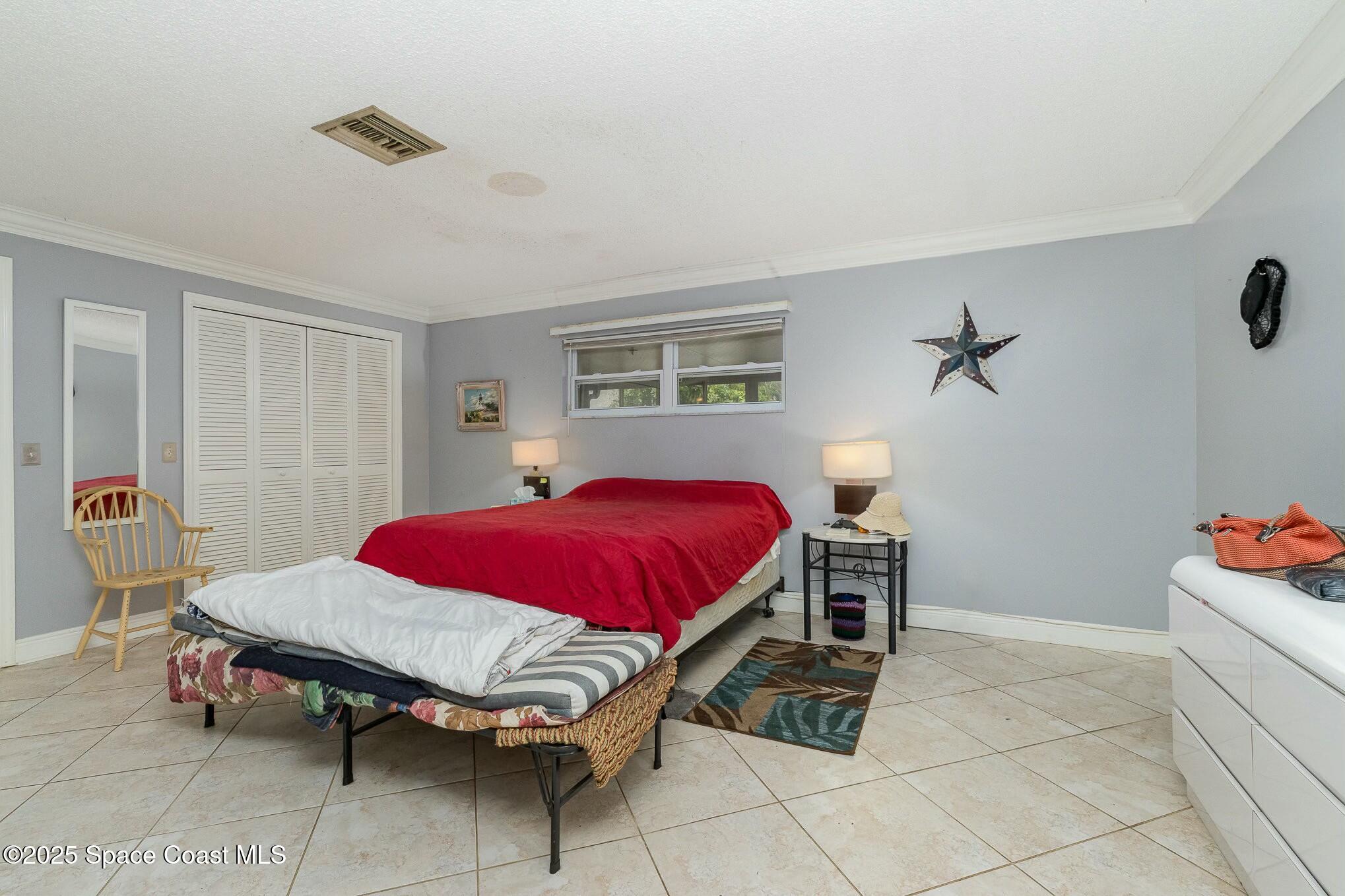 1351 Cherry Hills Road Northeast Palm Bay, FL 32905 - Photo 20 of 27 a spacious bedroom with a bed and a table