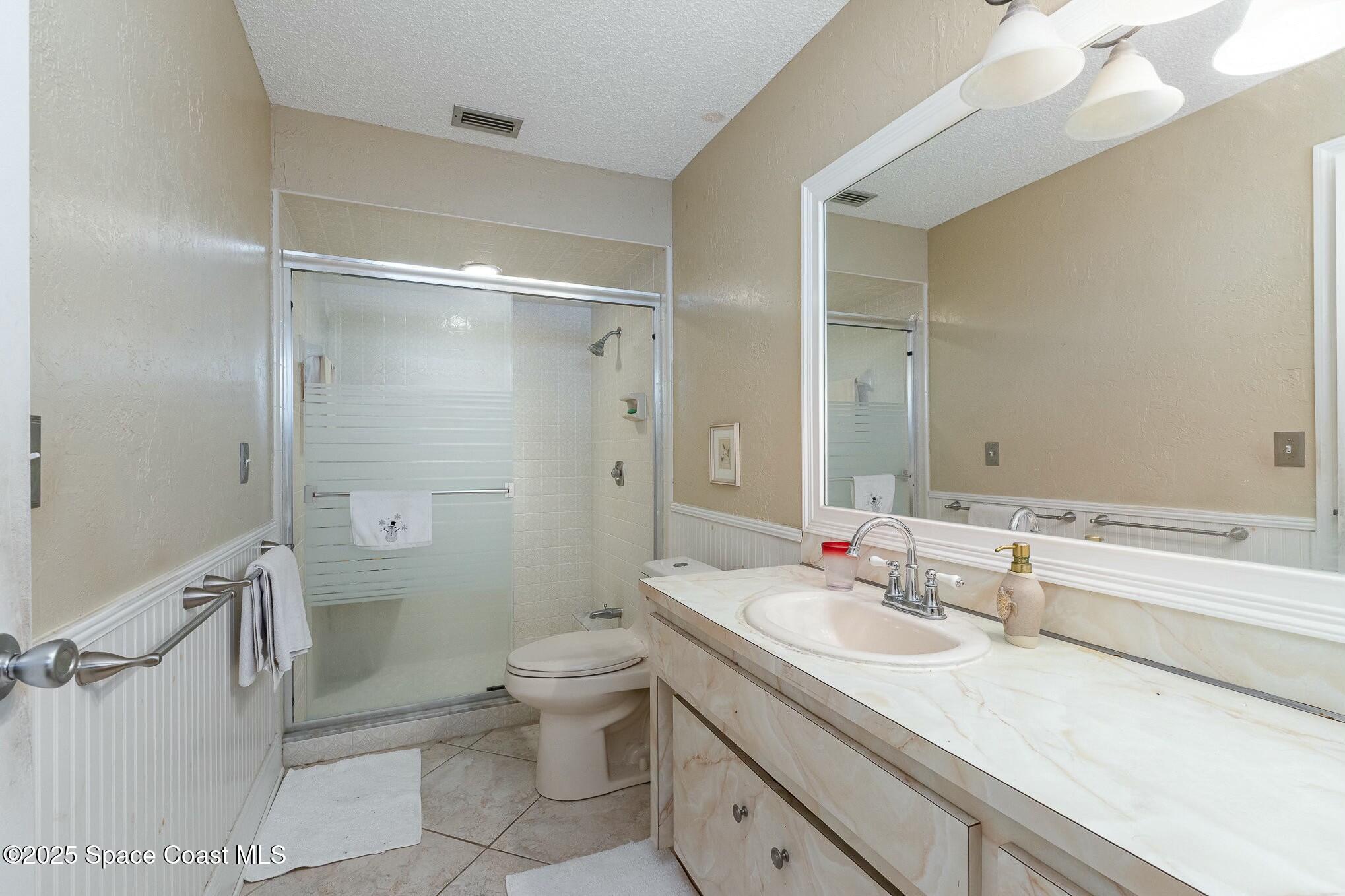 1351 Cherry Hills Road Northeast Palm Bay, FL 32905 - Photo 22 of 27 a bathroom with a double vanity sink toilet mirror and shower