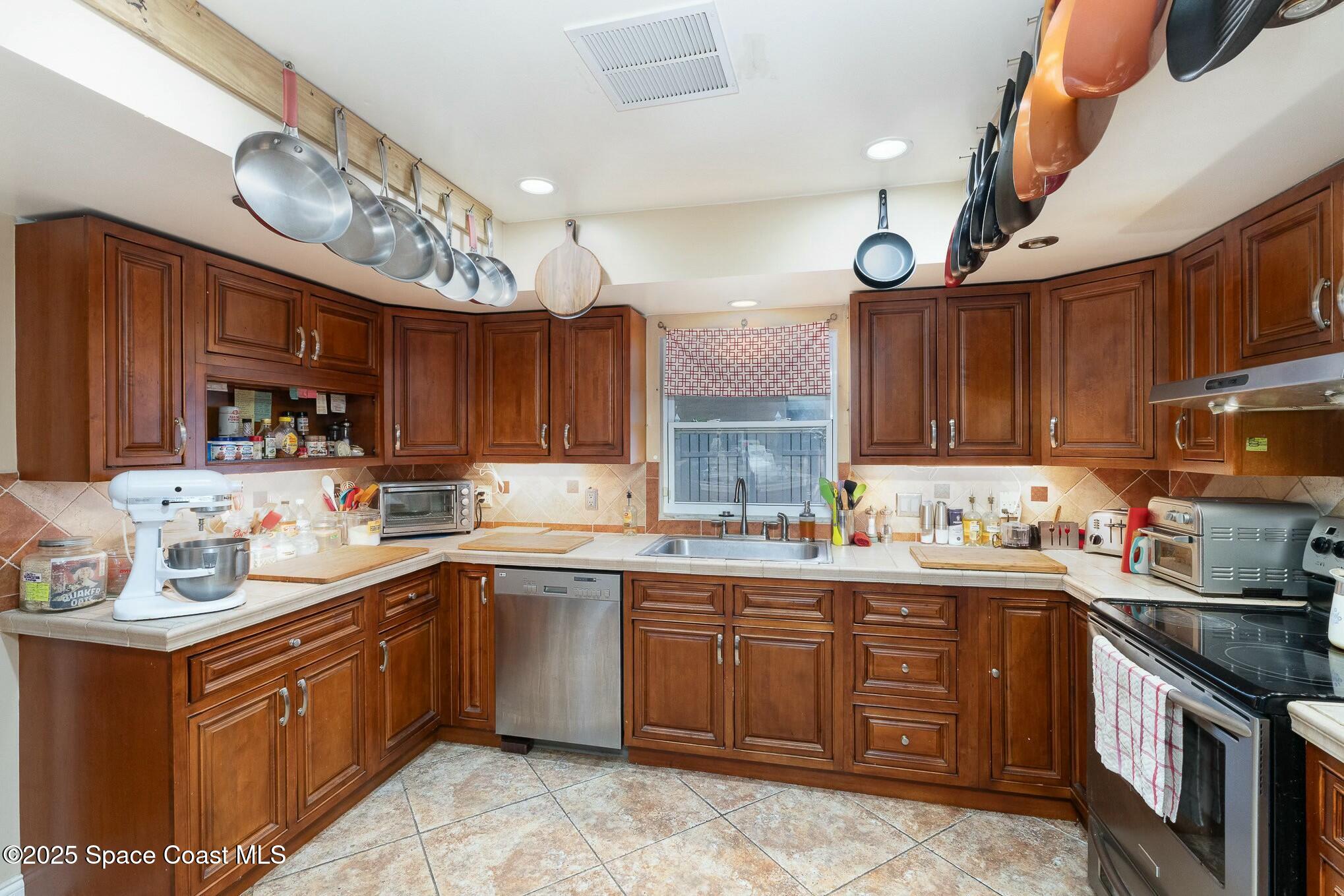 1351 Cherry Hills Road Northeast Palm Bay, FL 32905 - Photo 9 of 27 a kitchen with a sink a stove and cabinets