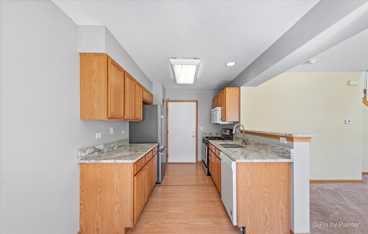 9433 Rainsford Drive, Unit 9433 Huntley, IL 60142 - Photo 12 of 30 a kitchen with stainless steel appliances granite countertop a stove a sink and a microwave