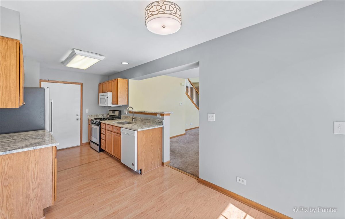 9433 Rainsford Drive, Unit 9433 Huntley, IL 60142 - Photo 13 of 30 a kitchen with granite countertop a stove a sink and a refrigerator