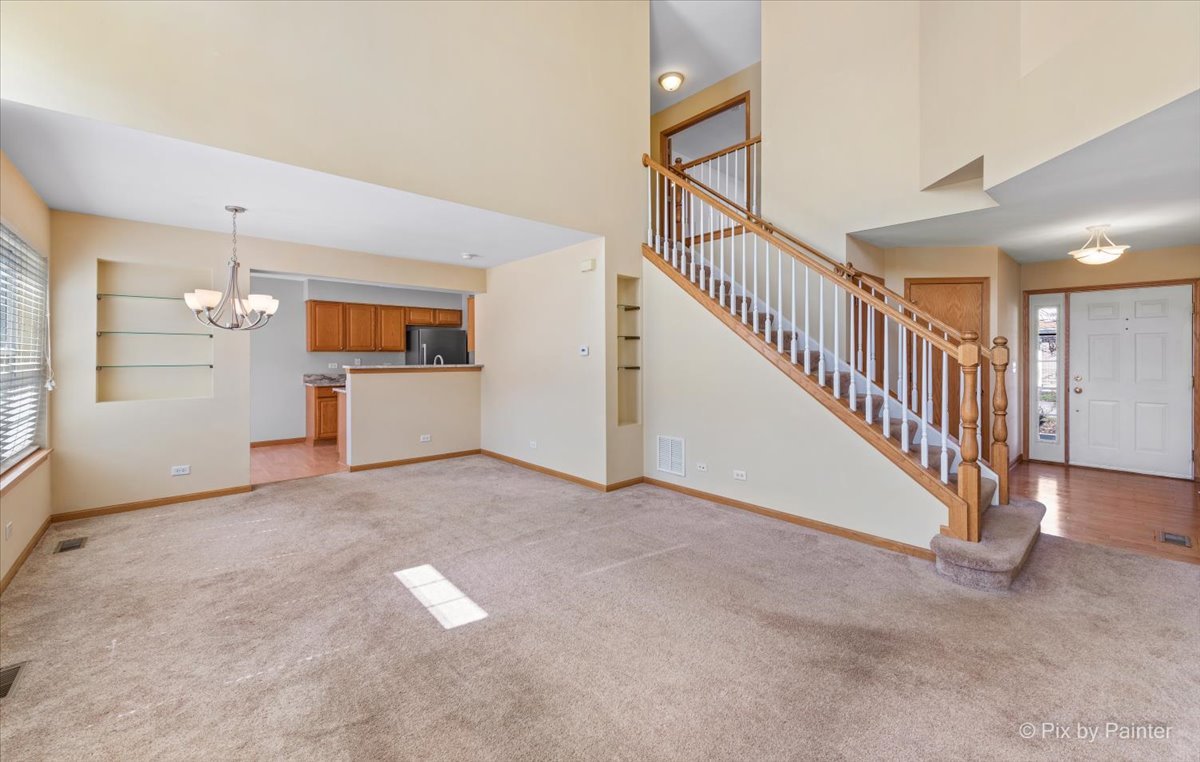 9433 Rainsford Drive, Unit 9433 Huntley, IL 60142 - Photo 6 of 30 a view of an empty room with stairs and a kitchen view