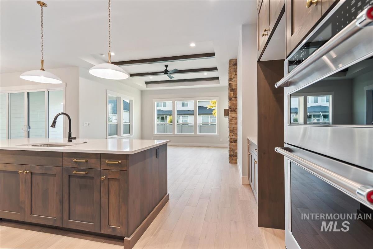 2147 East Blakehurst Avenue Kuna, ID 83634 - Photo 12 of 43 Kitchen featuring double oven, dark brown cabinets, decorative light fixtures, beamed ceiling, and light wood-style floors