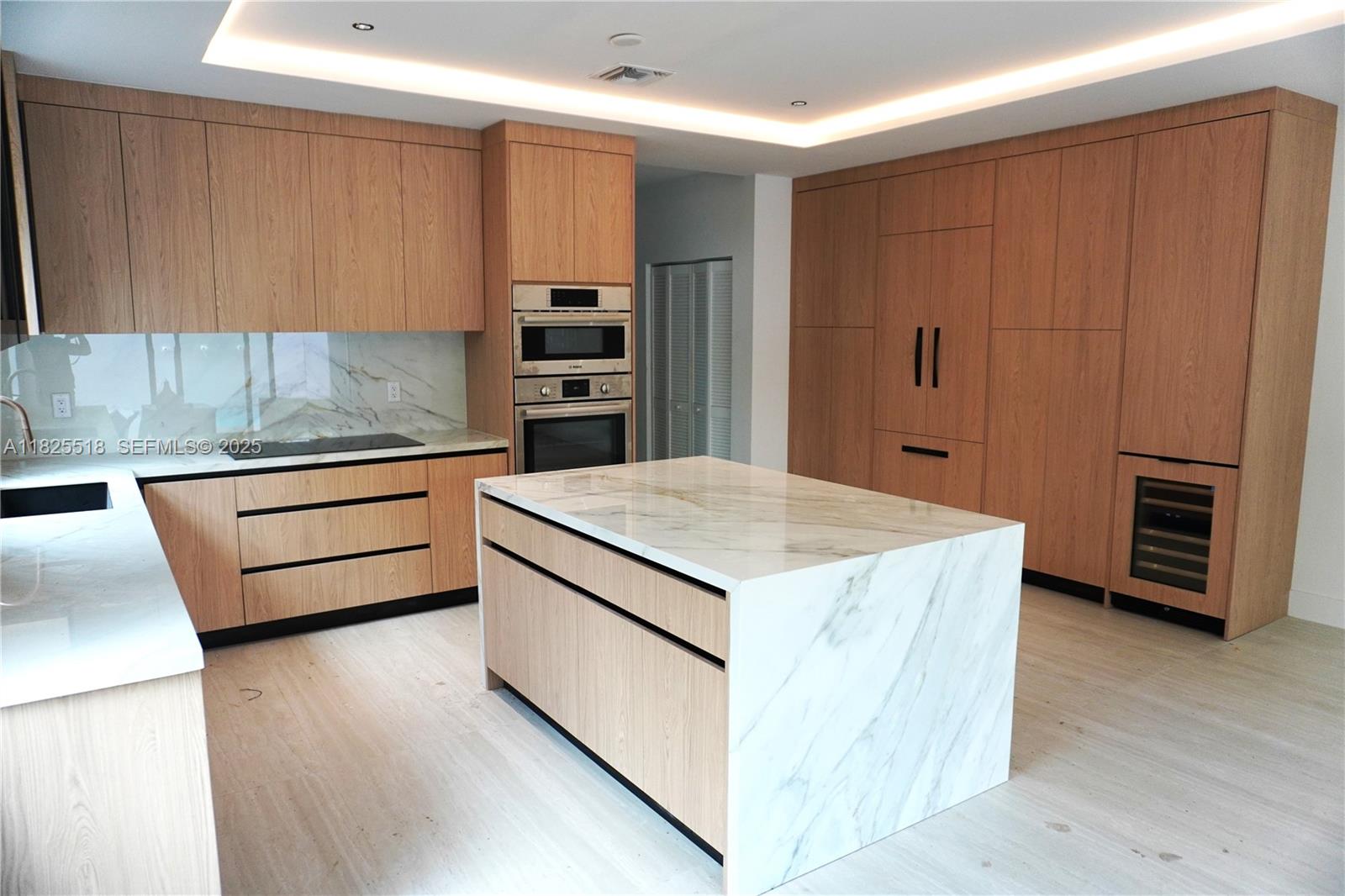 3187 Southwest 23rd Street, Unit A Miami, FL 33145 - Photo 3 of 16 a kitchen that has a kitchen island wooden cabinets and stainless steel appliances