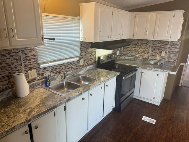 a kitchen with granite countertop a sink a stove and cabinets