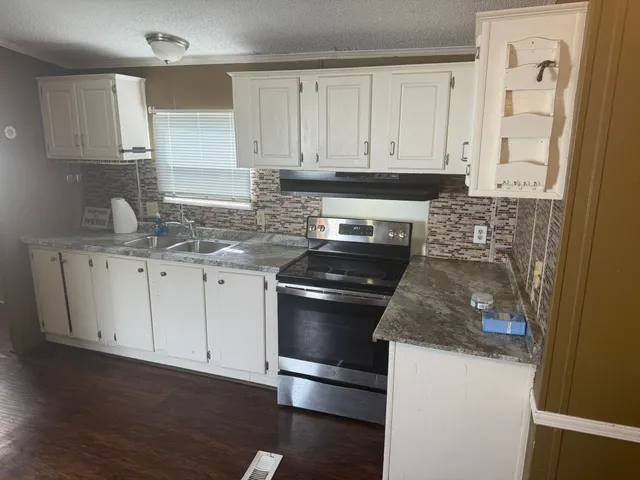 a kitchen with granite countertop a sink stainless steel appliances and cabinets