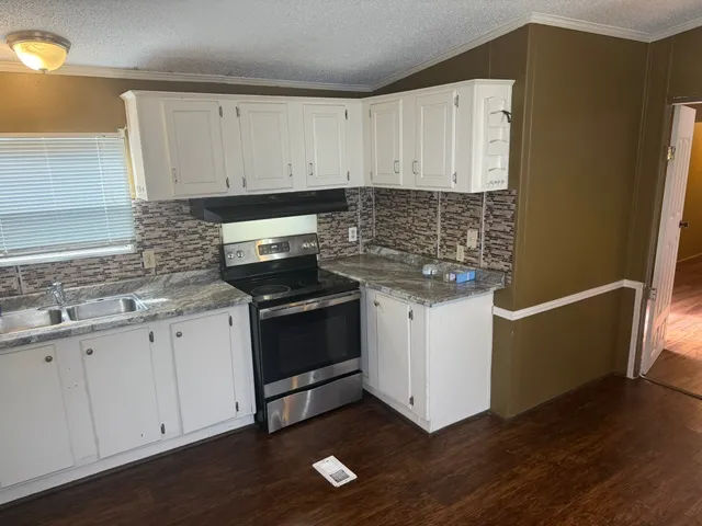 a kitchen with granite countertop white cabinets and black appliances