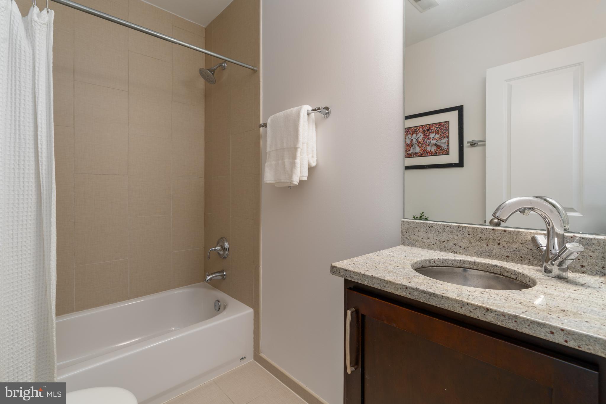 3465 14th Street Northwest, Unit D Washington, DC 20010 - Photo 16 of 24 a bathroom with a granite countertop sink a mirror a shower and bathtub