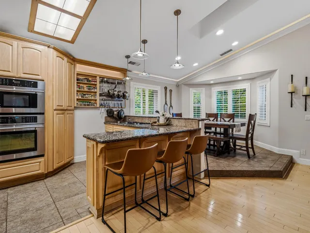 a kitchen with stainless steel appliances granite countertop table chairs and a refrigerator