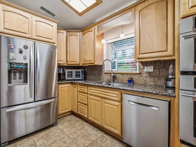 a kitchen with stainless steel appliances granite countertop a refrigerator a sink a stove and cabinets