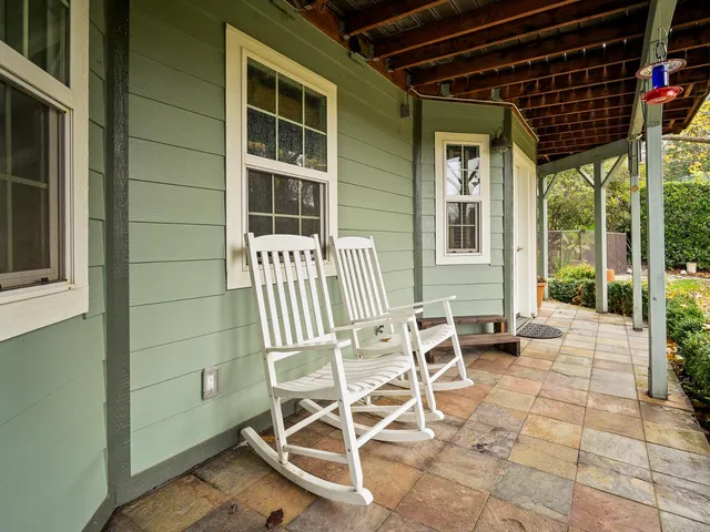 a patio with table and chairs and potted plants