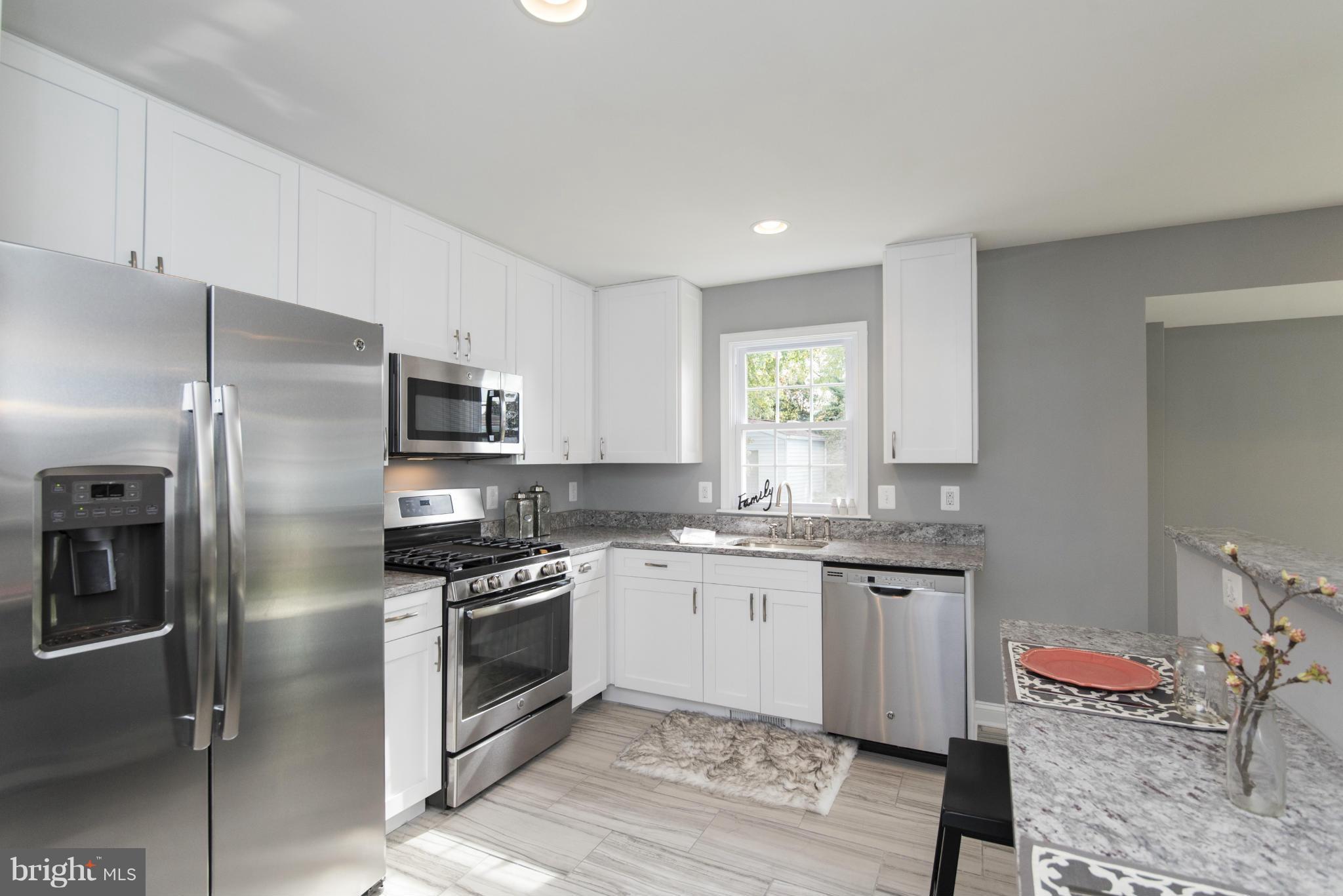 6705 Fordcrest Road Baltimore, MD 21237 - Photo 2 of 30 a kitchen with stainless steel appliances granite countertop a stove a sink dishwasher a refrigerator and white cabinets with wooden floor