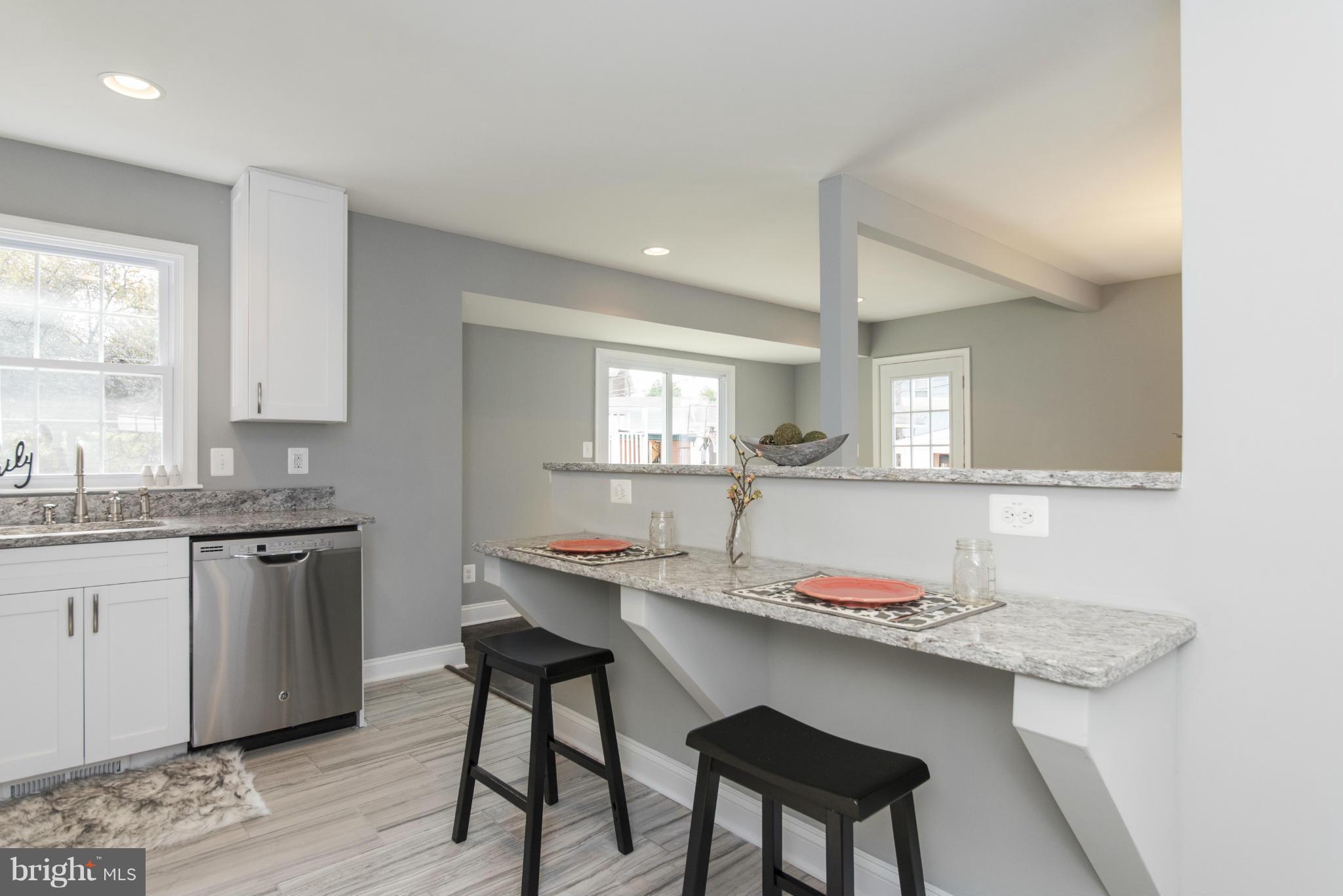 6705 Fordcrest Road Baltimore, MD 21237 - Photo 3 of 30 a kitchen with granite countertop a sink white cabinets and chairs