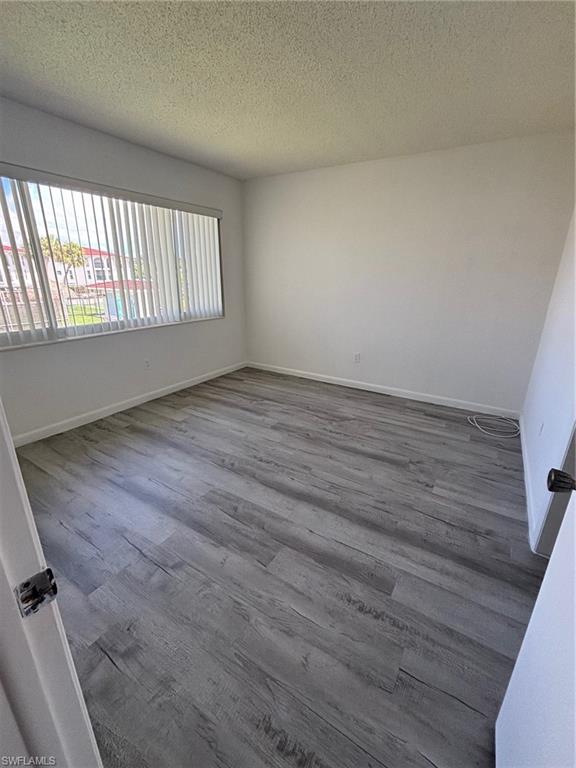 3250 10th Street North, Unit A8 Naples, FL 34103 - Photo 8 of 13 wooden floor in an empty room with a window