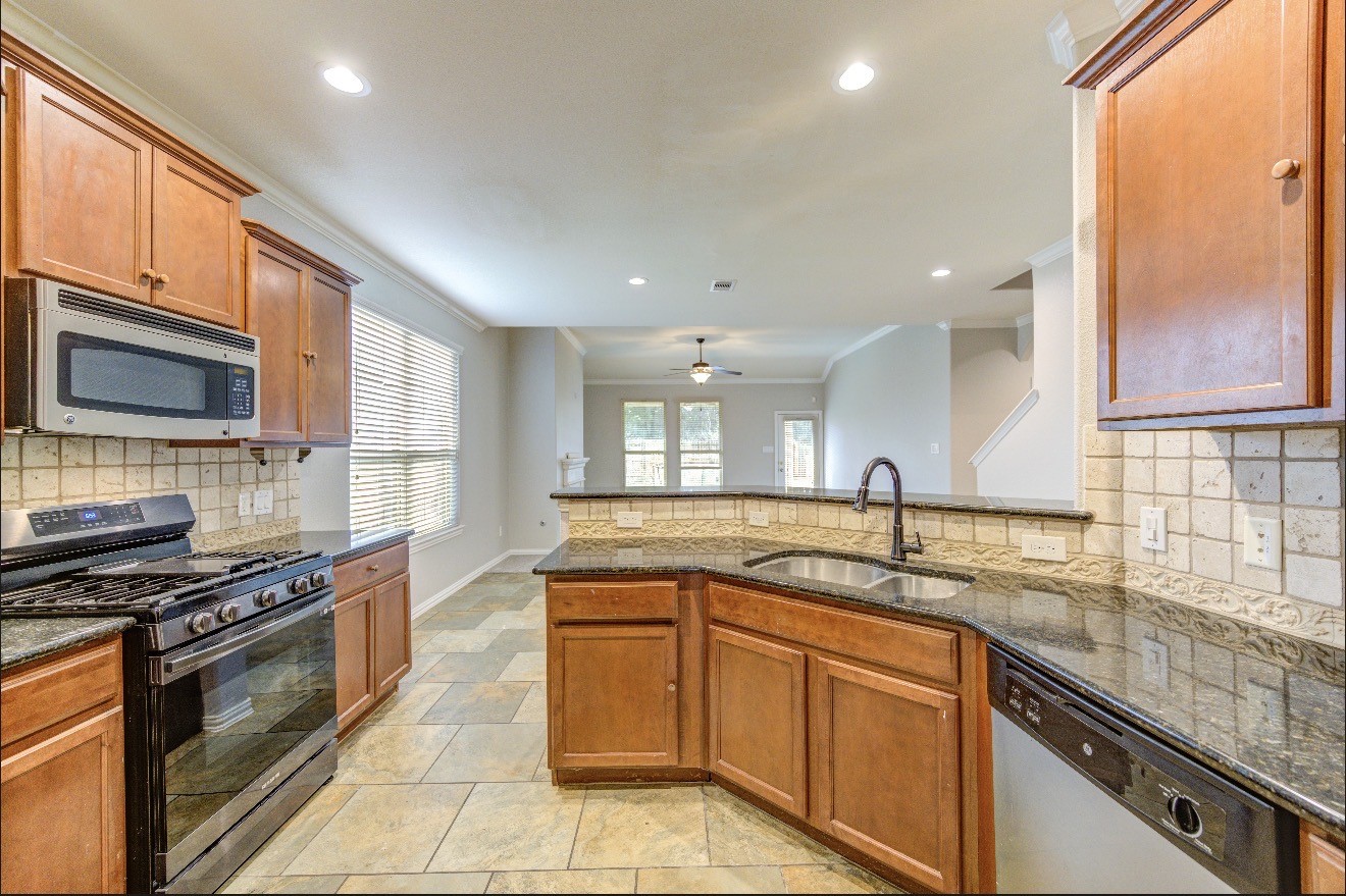 7 Maple Mill Court Conroe, TX 77301 - Photo 22 of 49 a kitchen with stainless steel appliances granite countertop a sink stove and cabinets