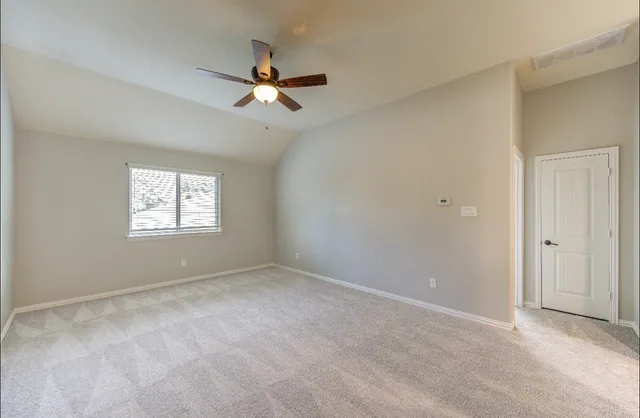 an empty room with closet and a ceiling fan