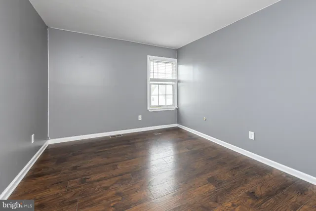 a view of an empty room with wooden floor and window