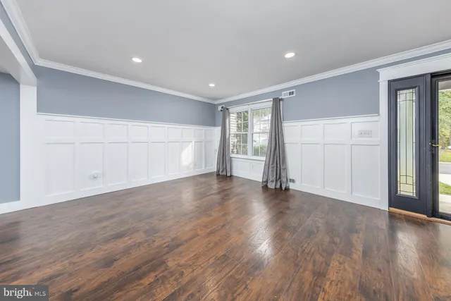 a view of an empty room with wooden floor and window