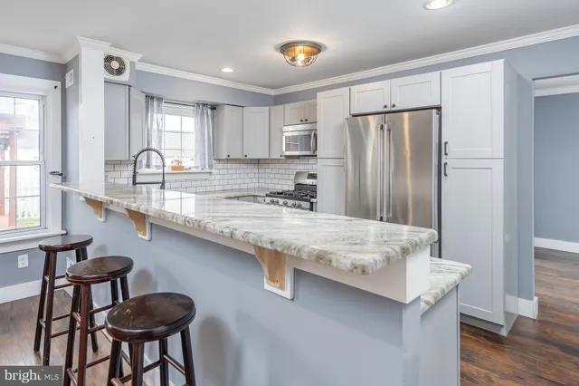 a kitchen with stainless steel appliances granite countertop a sink a stove a refrigerator a table and chairs