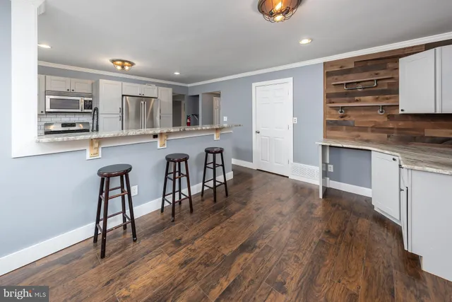 a kitchen with stainless steel appliances granite countertop a stove top oven a sink a dining table and chairs with wooden floor