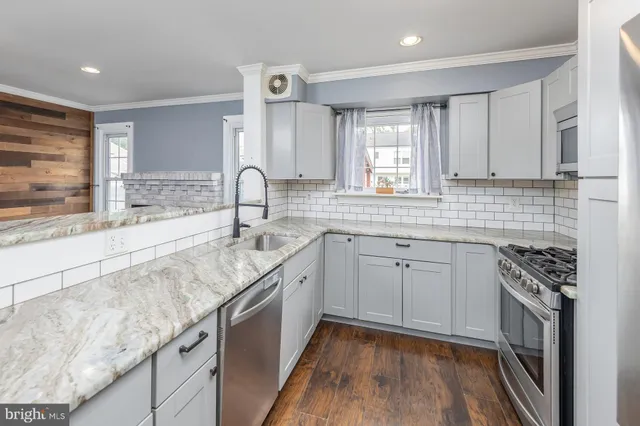 a kitchen with granite countertop a sink stainless steel appliances and cabinets