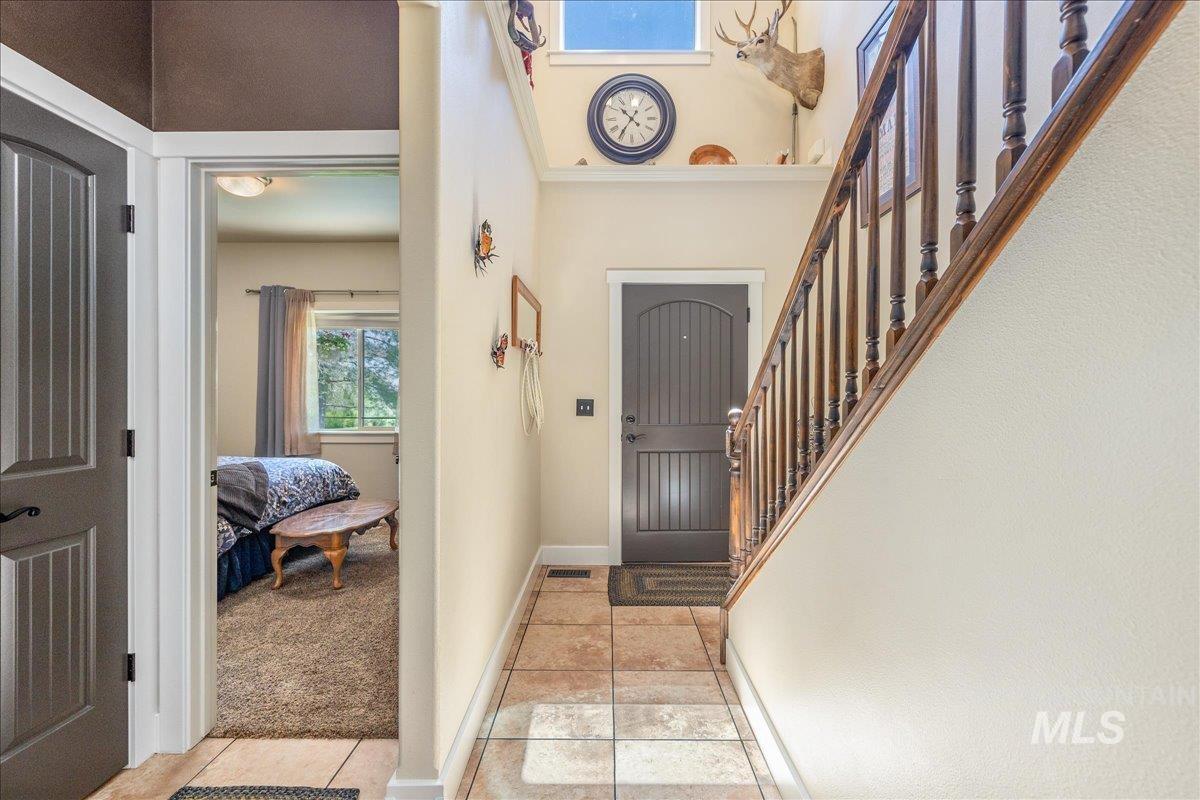 18593 South Pleasant Valley Road Kuna, ID 83634 - Photo 17 of 46 Entryway featuring tile flooring, a dark paneled door, and a wood staircase with balusters