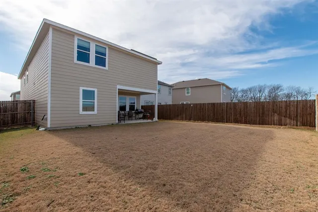 a view of a house with wooden fence next to a yard