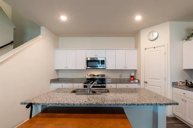 a kitchen with granite countertop a sink a stove and a refrigerator