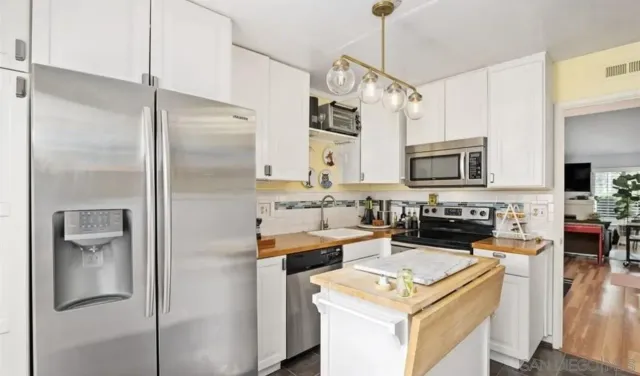 a kitchen with stainless steel appliances granite countertop a refrigerator a stove and a sink with wooden floor