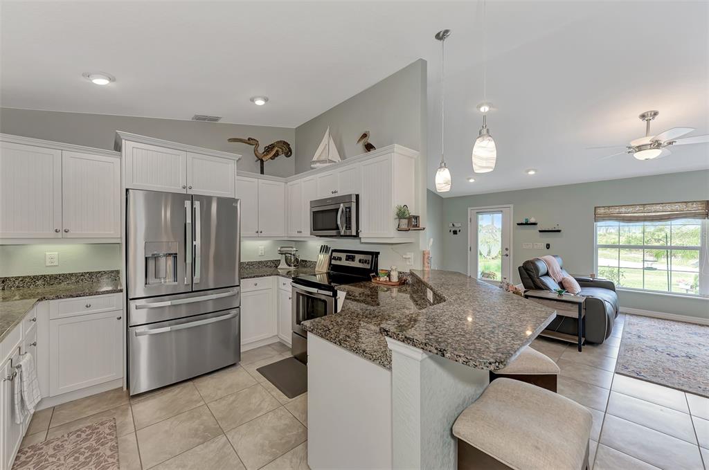 8 Amidship Road Placida, FL 33946 - Photo 11 of 47 a kitchen with granite countertop kitchen island stainless steel appliances a refrigerator a stove a sink a dining table and chairs with wooden floor