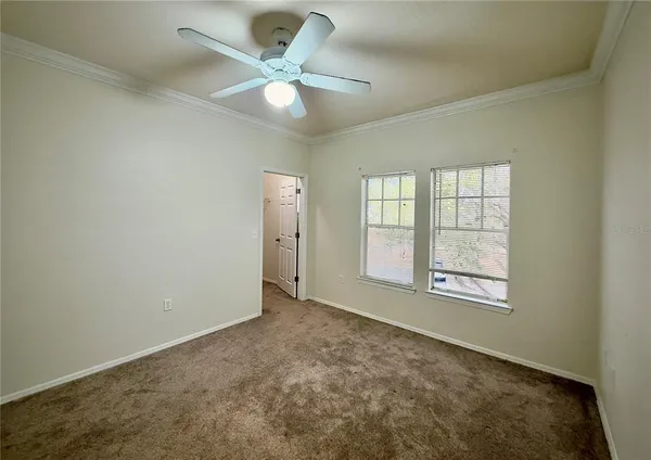 an empty room with chandelier fan and windows