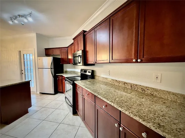 a kitchen with stainless steel appliances granite countertop a refrigerator a stove and a sink
